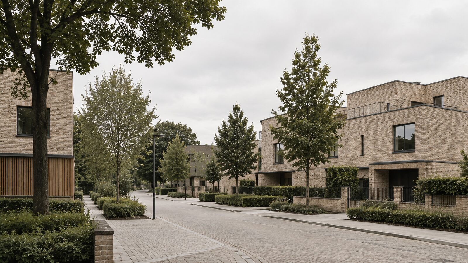A tree-lined residential street of contemporary brick townhouses, photographed on an overcast day